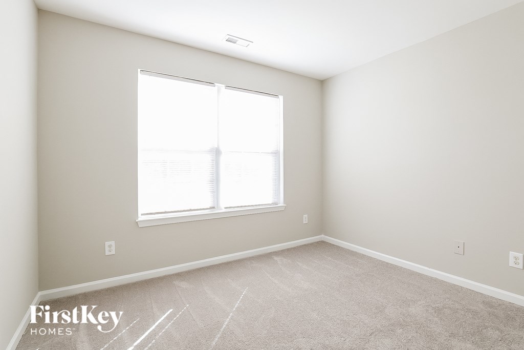a bedroom with a large window and a carpeted floor