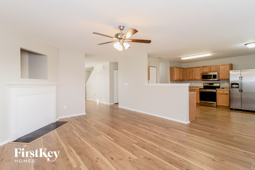 a living room and kitchen with wood flooring and a ceiling fan