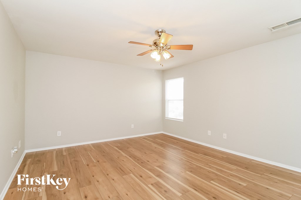 a spacious living room with hardwood floors and a ceiling fan