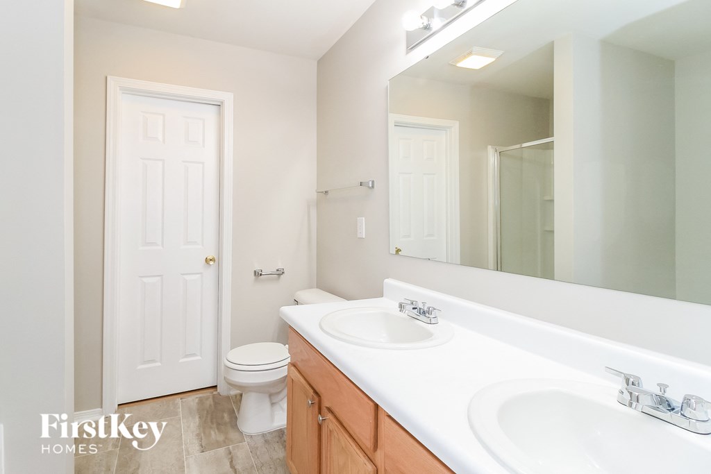 a bathroom with two sinks and a toilet and a large mirror