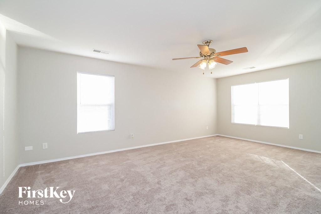 a empty room with a ceiling fan and two windows