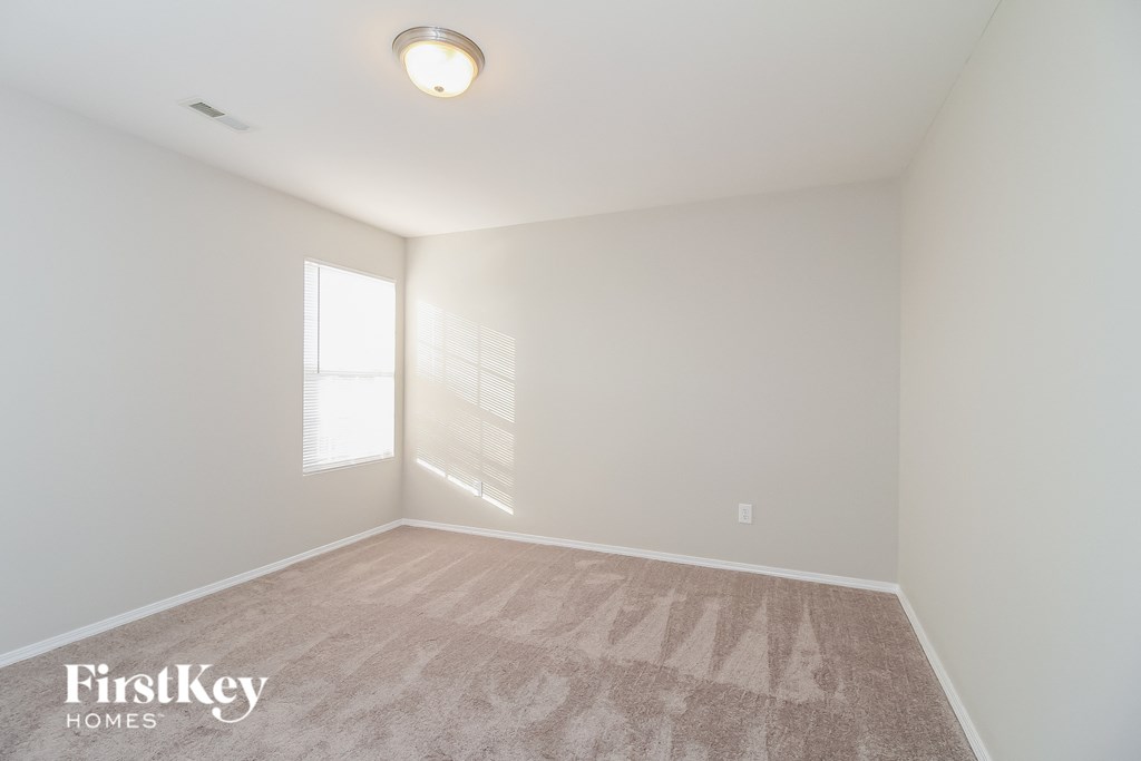 a bedroom with white walls and carpet and a window