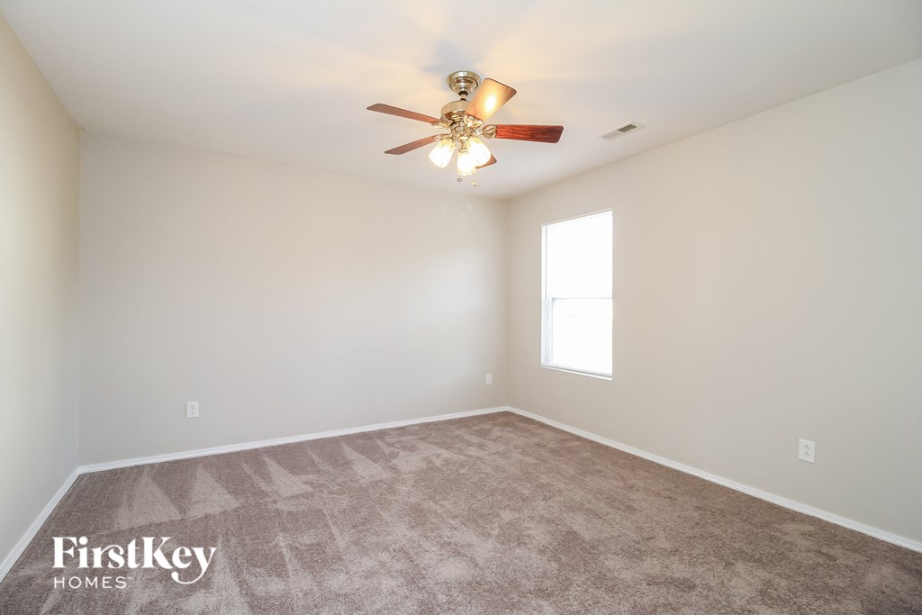 the spacious living room with ceiling fan and carpet