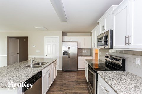 A kitchen with white cabinets and a granite countertop.