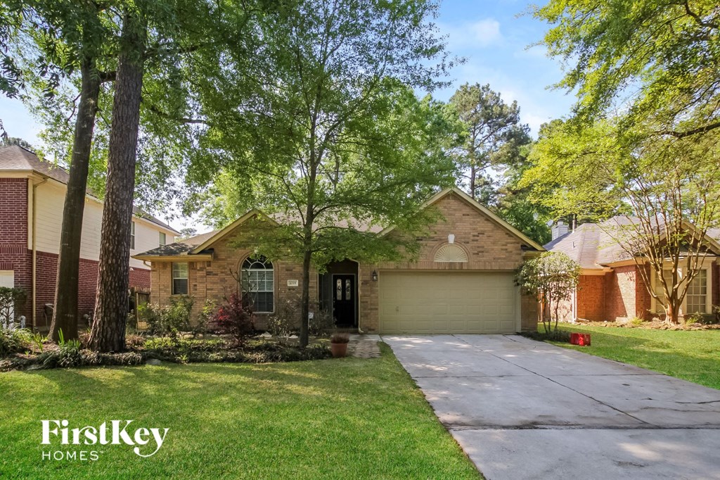 front view of a brick house with a driveway and trees