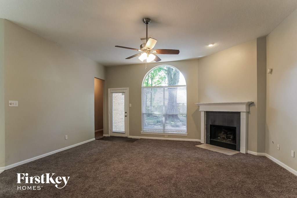 an empty living room with a fireplace and a ceiling fan