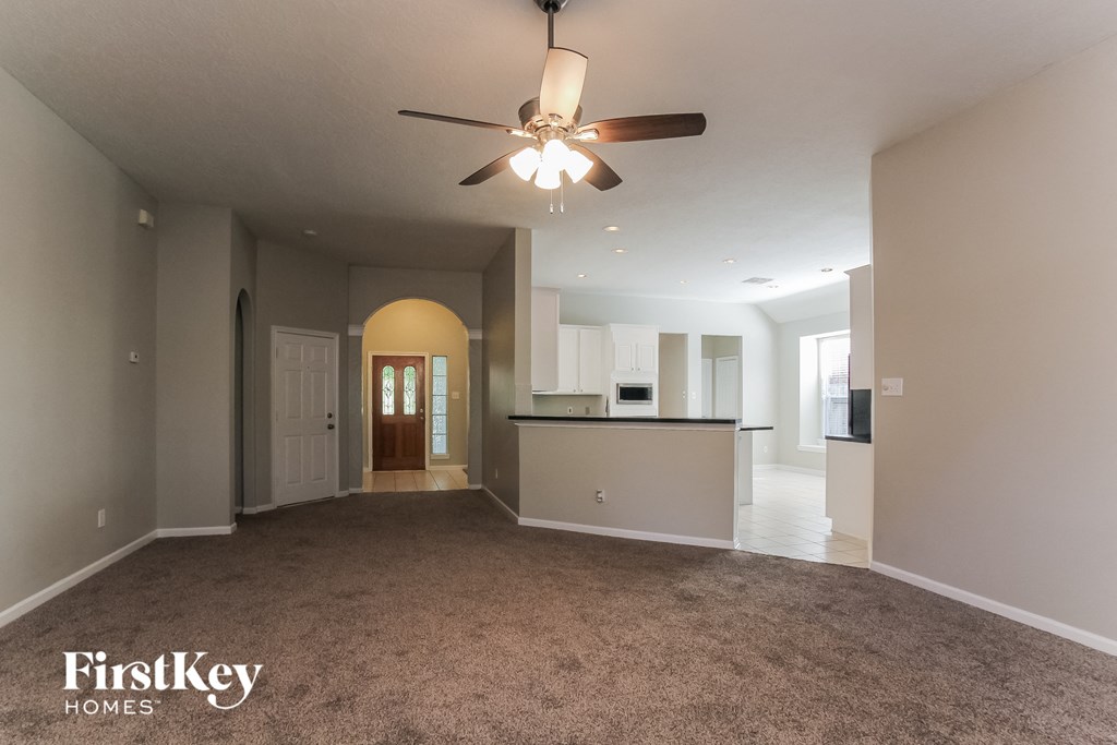 an empty living room and kitchen with a ceiling fan