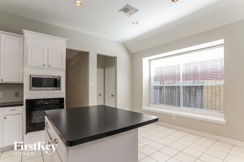 a kitchen with white cabinets and a black counter top