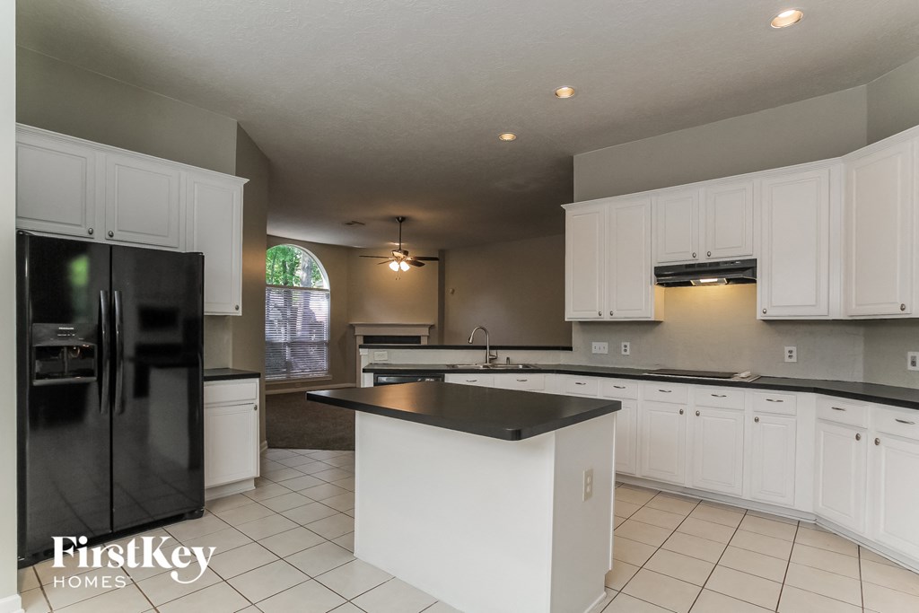 a large kitchen with white cabinets and black counter tops