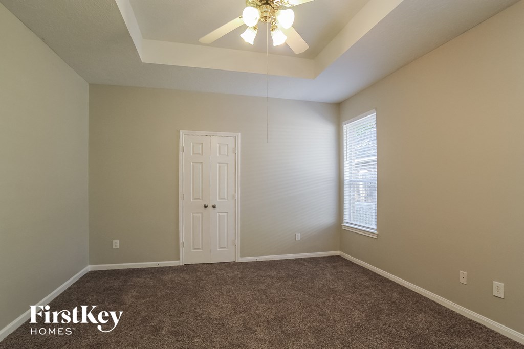 an empty room with a white door and a ceiling fan