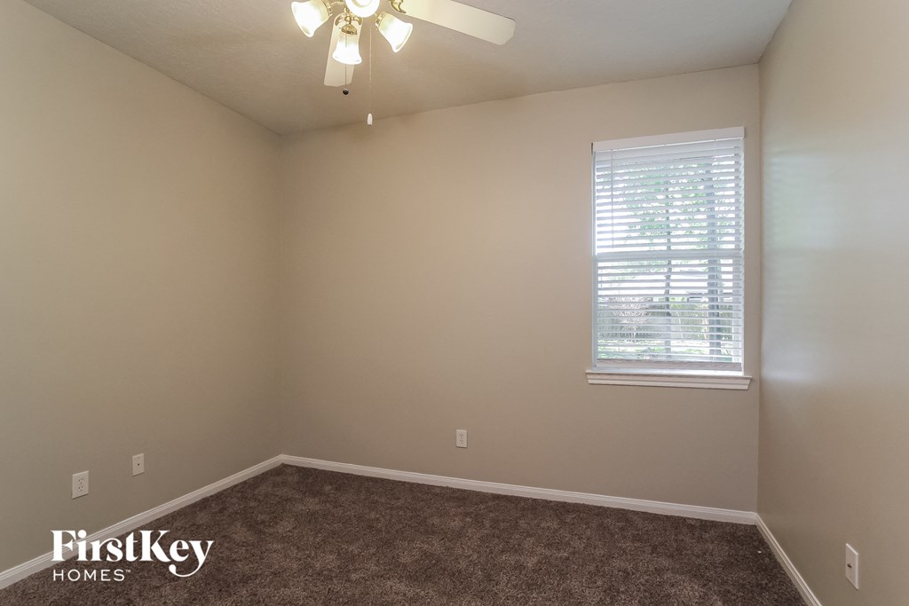 the upstairs bedroom has a carpeted floor and a ceiling fan
