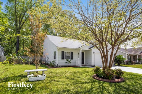 a small white house with a yard and a bench