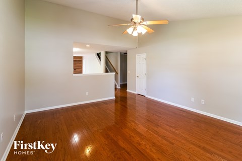 an empty living room with wood floors and a ceiling fan