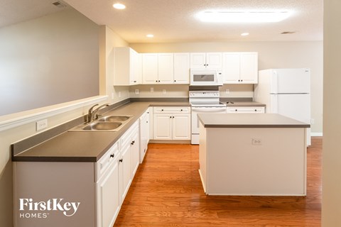 a kitchen with white cabinets and white appliances and a wooden floor