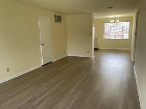 an empty living room with wood floors and a window