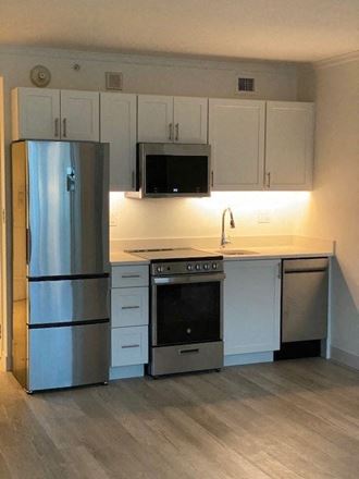 a kitchen with white cabinets and a stainless steel refrigerator