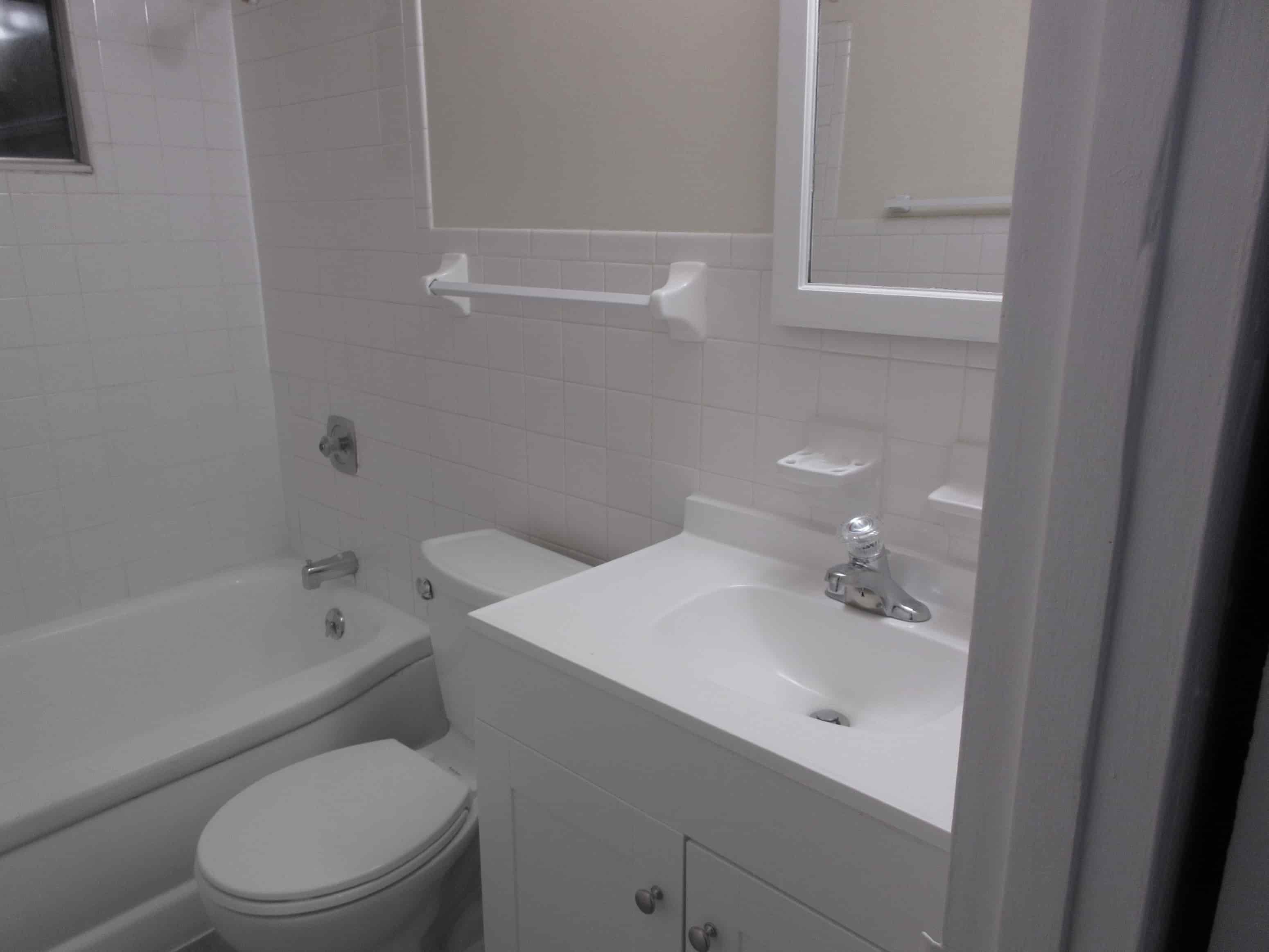 A white toilet sits next to a white sink in a bathroom.