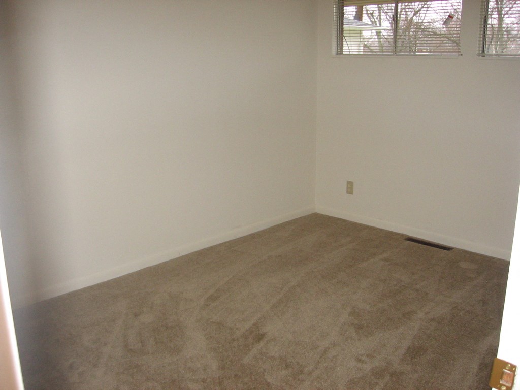 an empty room with a carpeted floor and a window