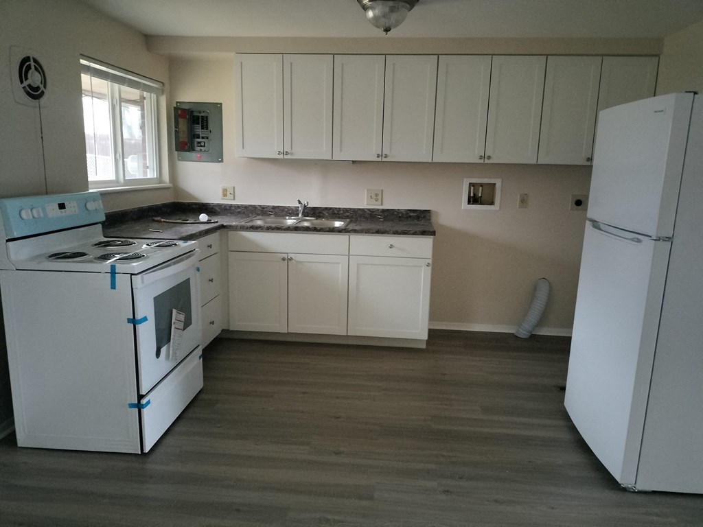an empty kitchen with white appliances and white cabinets