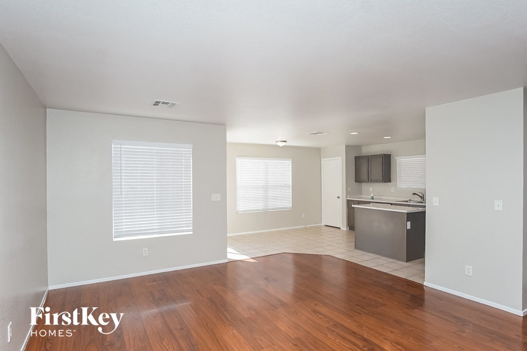 A spacious empty room with wooden floors and white walls.