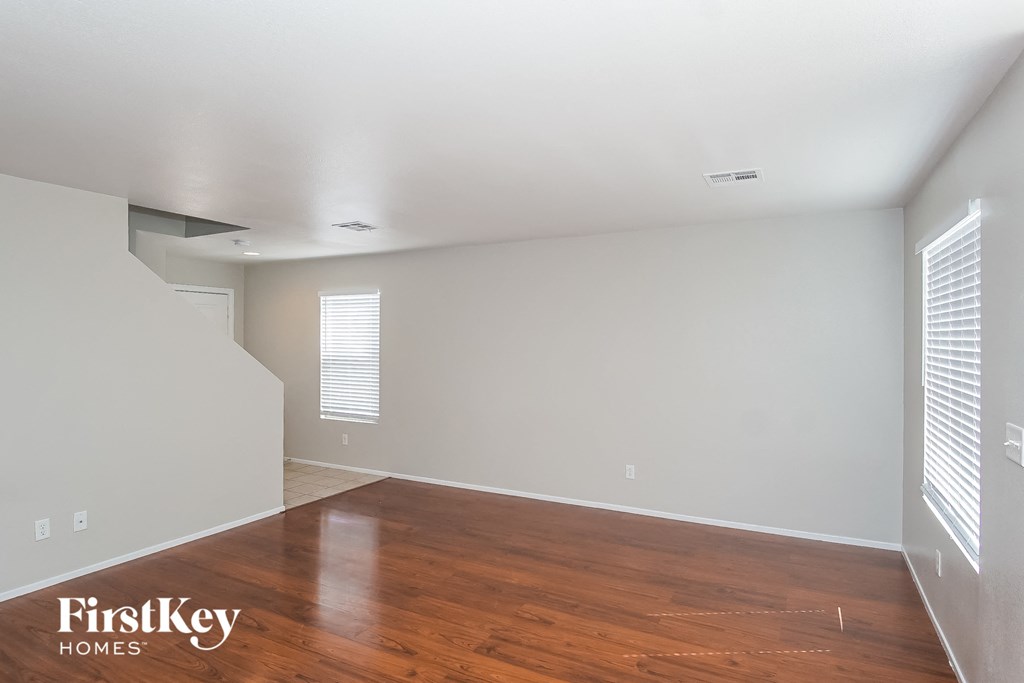 A room with wooden floors and white walls, with a FirstKey Homes logo on the bottom left.