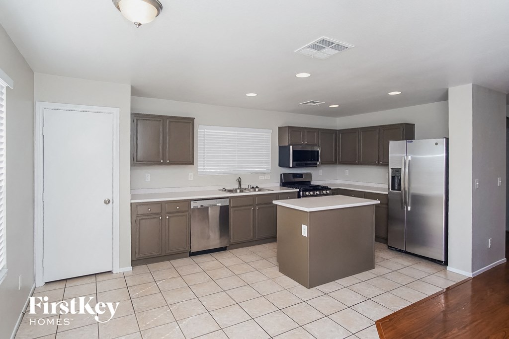 A kitchen with a refrigerator, microwave, and oven.