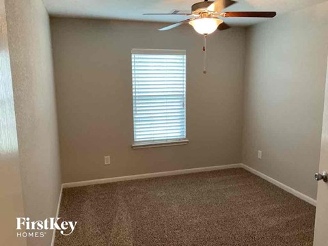 A room with a ceiling fan and a window with blinds.
