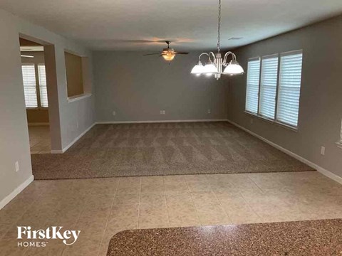A spacious room with a rug on the floor and a chandelier hanging from the ceiling.