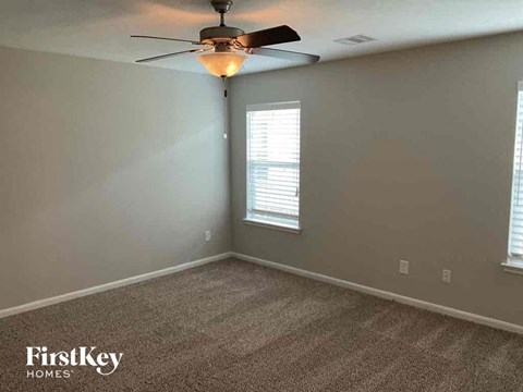 A room with a carpet floor and a ceiling fan.