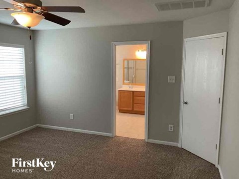 A room with a carpeted floor and a ceiling fan.
