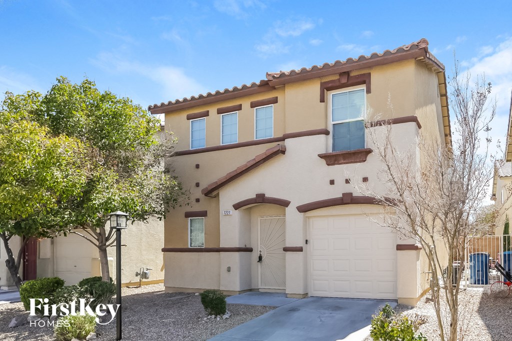 A beige house with a brown roof and a garage door.