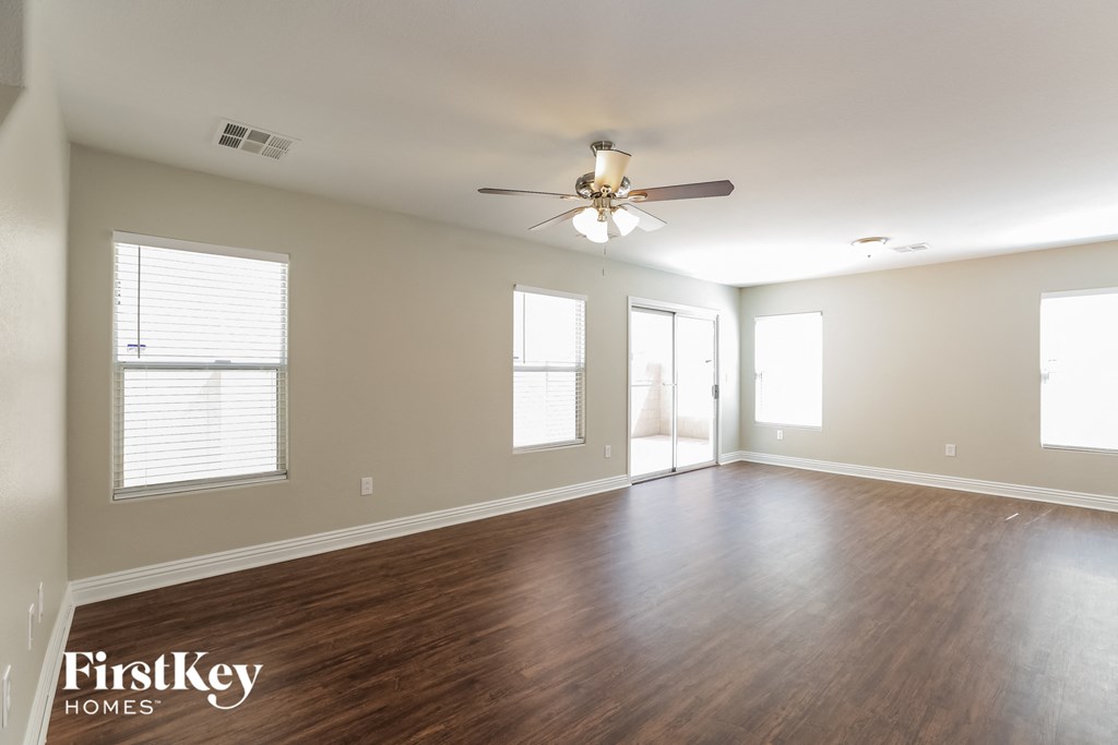 A spacious room with wooden floors and a ceiling fan.