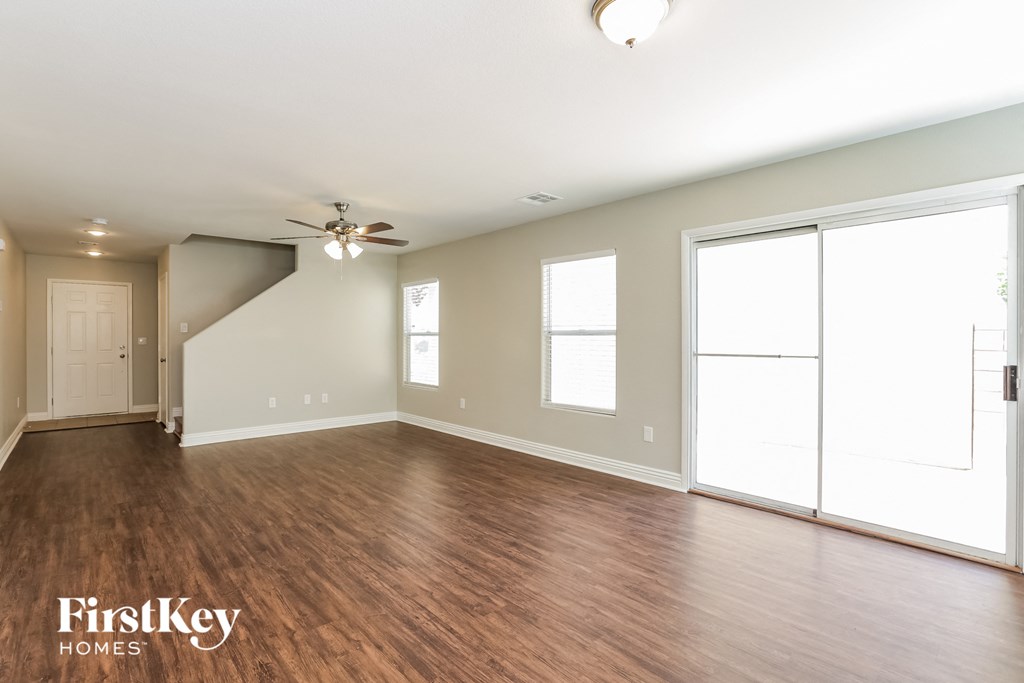 A spacious room with wooden floors and a ceiling fan.