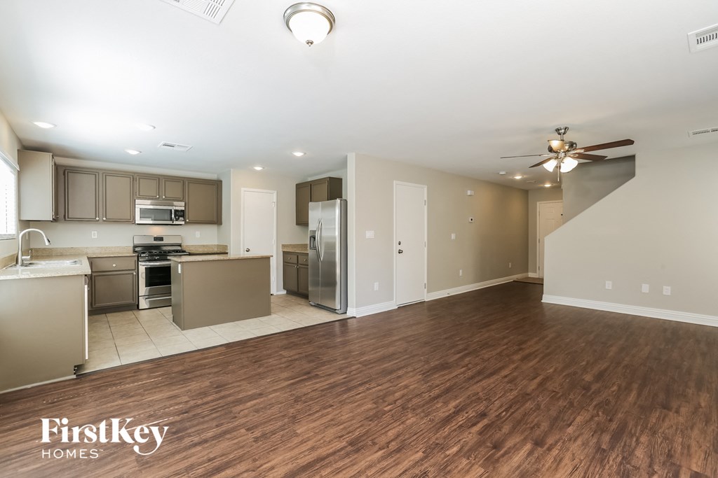 A spacious kitchen and living room with wooden floors and a staircase.