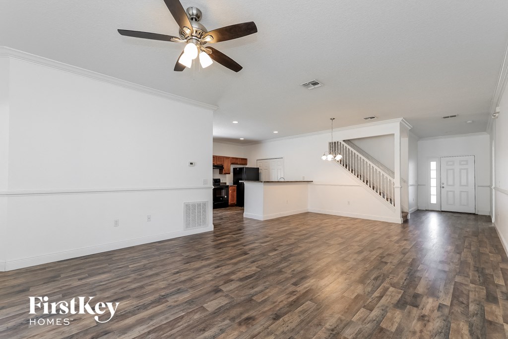 A spacious room with wooden floors and a ceiling fan.