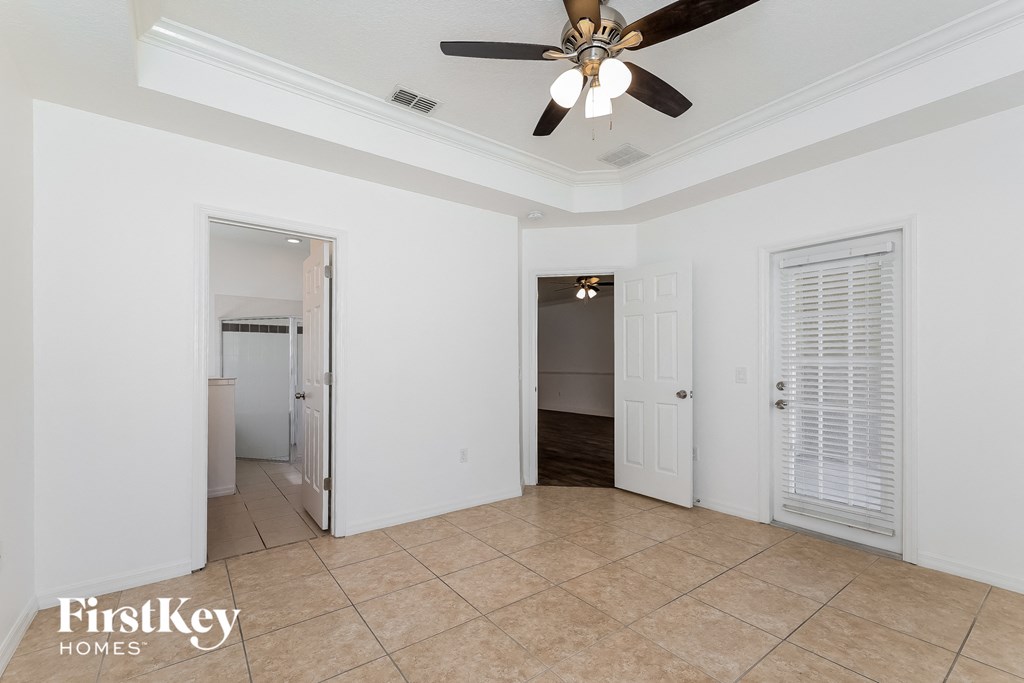 A spacious room with a ceiling fan and tiled flooring.