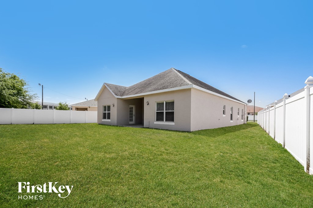 A house with a white fence and a grassy yard.