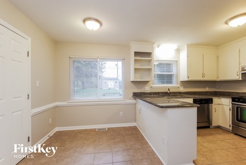 A kitchen with a white counter top and stove top oven.