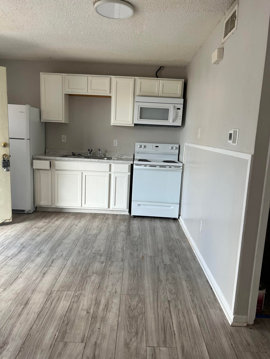 an empty kitchen with white appliances and white cabinets