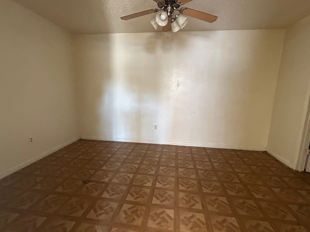 an empty living room with a ceiling fan