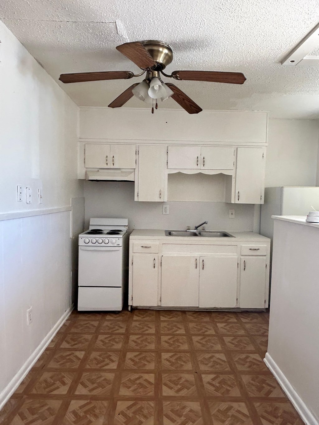 a kitchen with white appliances and a ceiling fan