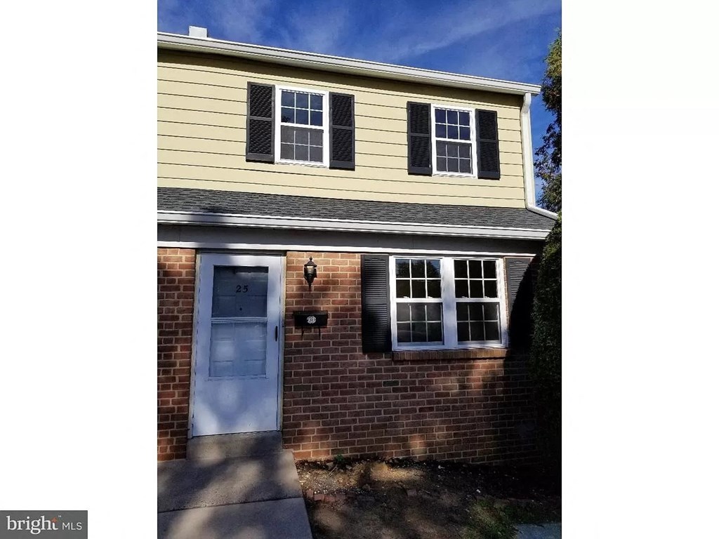 the front of a brick house with a white door and black windows