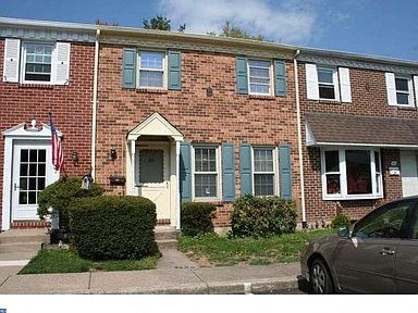 a brick house with blue shutters and a car parked in front