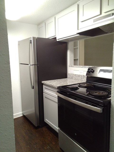 A black stove top oven sits next to a black refrigerator in a kitchen.