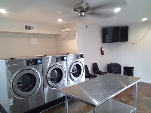 A room with a washer and dryer on the wall and a table in the middle.