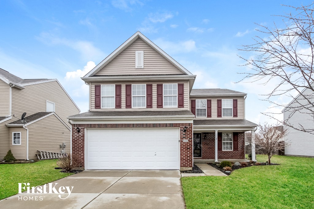 a house with a white garage door in front of a green lawn