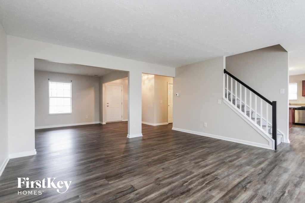 the living room and dining room of an empty house with wood flooring