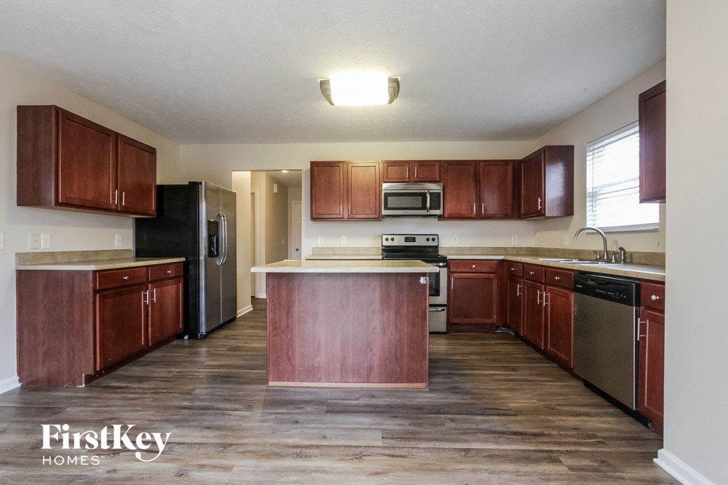 an empty kitchen with wooden cabinets and stainless steel appliances