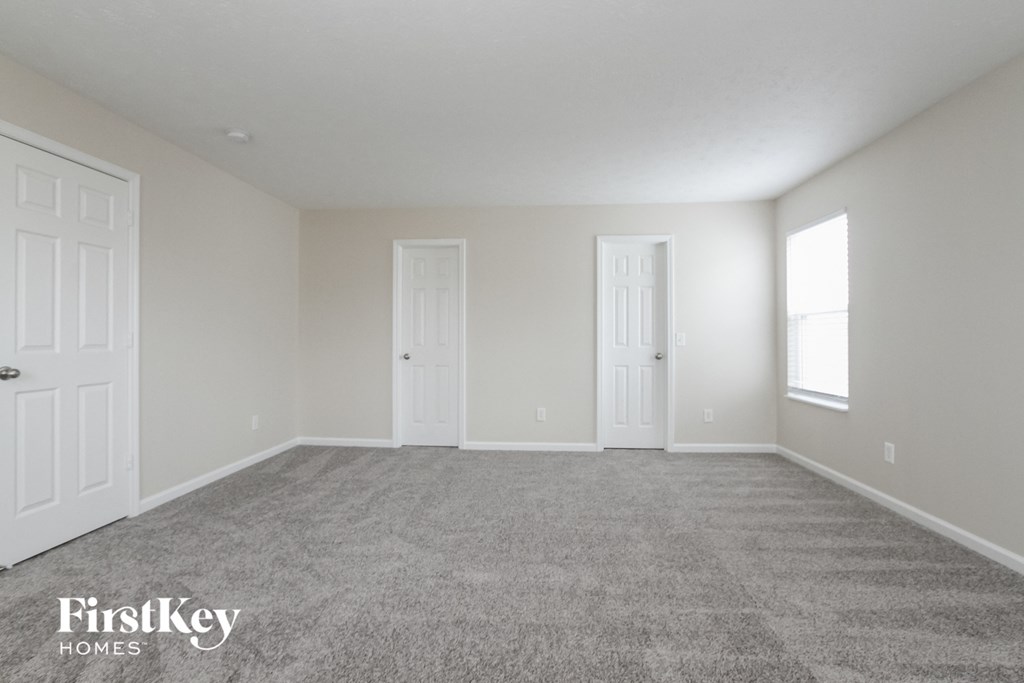 a room with carpet and two doors and a window