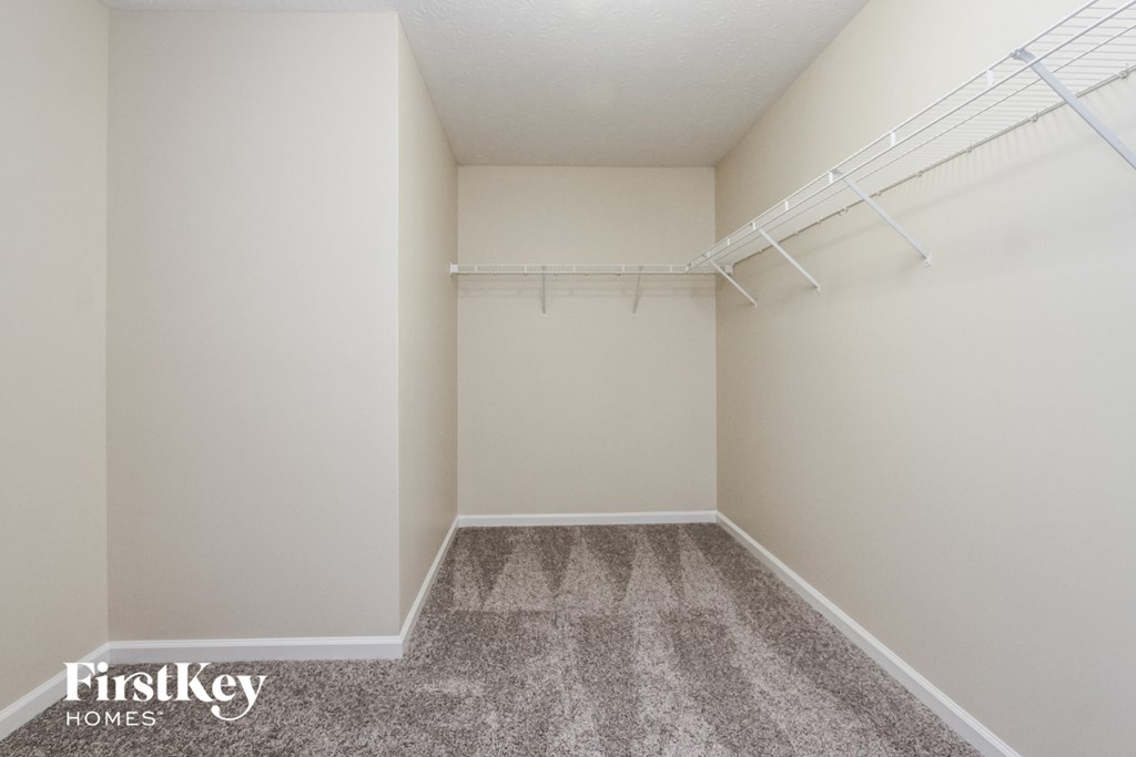 a spacious closet with white rods and a carpeted floor